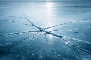 Cracked blue ice surface with subtle branching fractures, representing hidden legal risk in Ontario termination clauses.