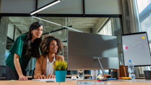 Employees reviewing AI-generated work on a computer in an office, highlighting the importance of AI expert oversight and responsible workplace AI use.