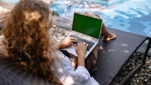 Person working remotely on a laptop beside a swimming pool, illustrating remote worker management, employee accountability, and flexible work arrangements.